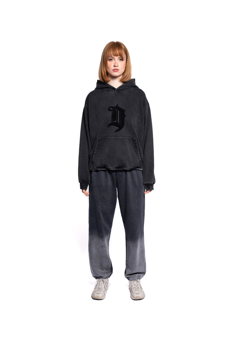 Junge Frau präsentiert den oversized black D Lab Hoodie, kombiniert mit passender Jogginghose