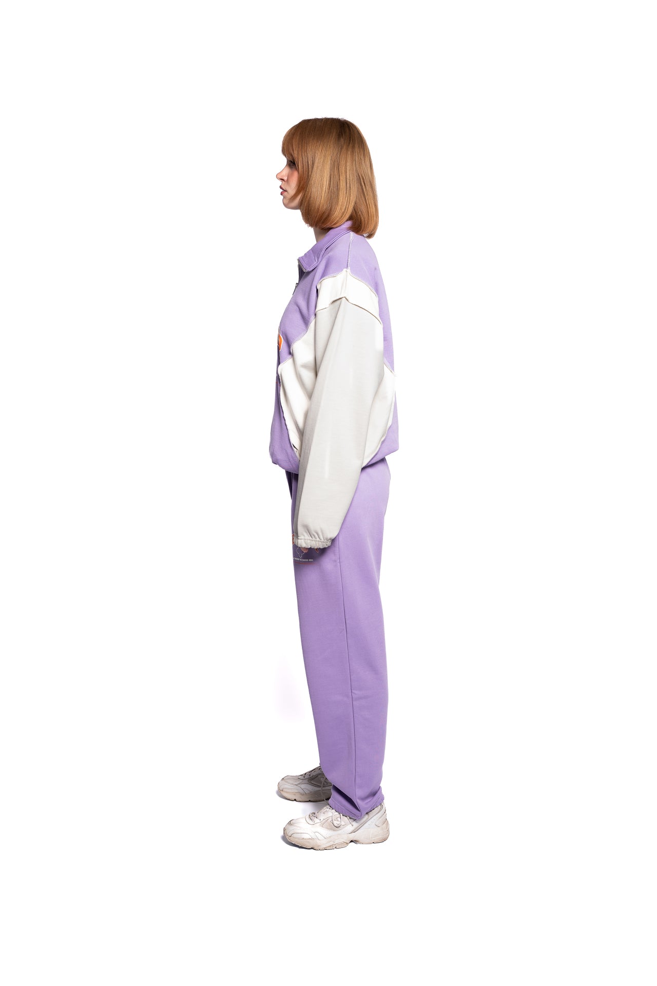 Seitenansicht des DeciderOutfits für Damen, lila Sweater gepaart mit passender Hose, stilvolle Farbkontraste, dargestellt von einem weiblichen Model.