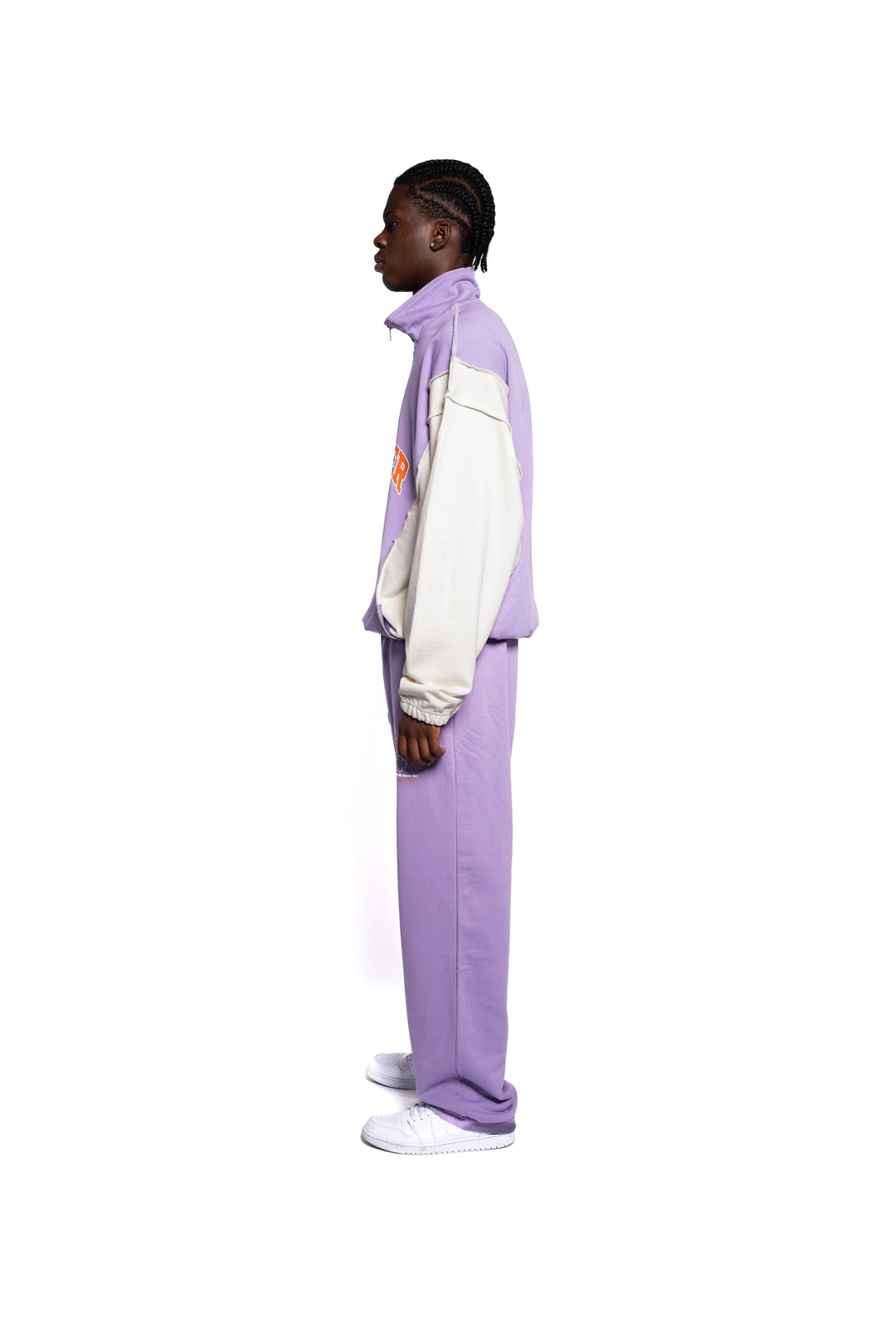 Seitenprofil des Decider Streetwear-Outfits, bestehend aus lila Hoodie und Hose mit Logo-Akzenten, getragen von einem männlichen Model