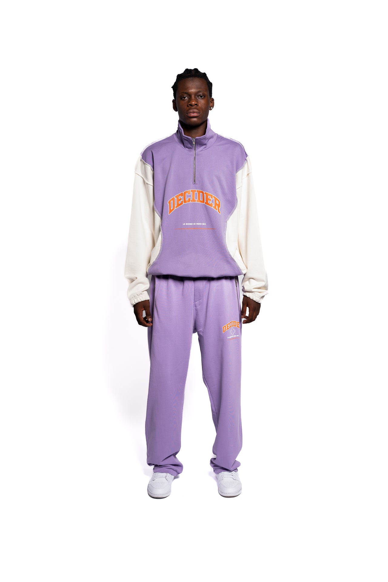 Urbaner Streetwear-Look mit Decider Herren-Set aus lila Hoodie und Jogginghose, mit markantem orangefarbenem Branding, präsentiert von einem männlichen Model.