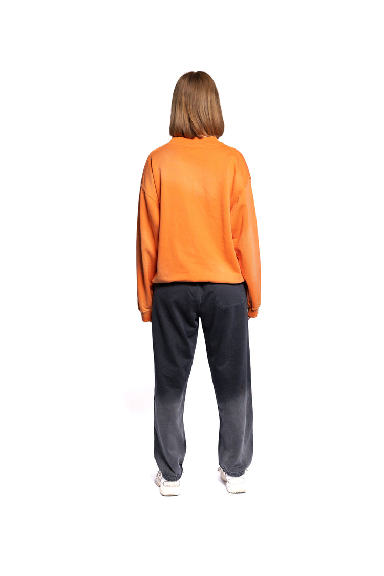 Rückansicht des weiblichen Models im orangefarbenen Hoodie ohne Kapuze