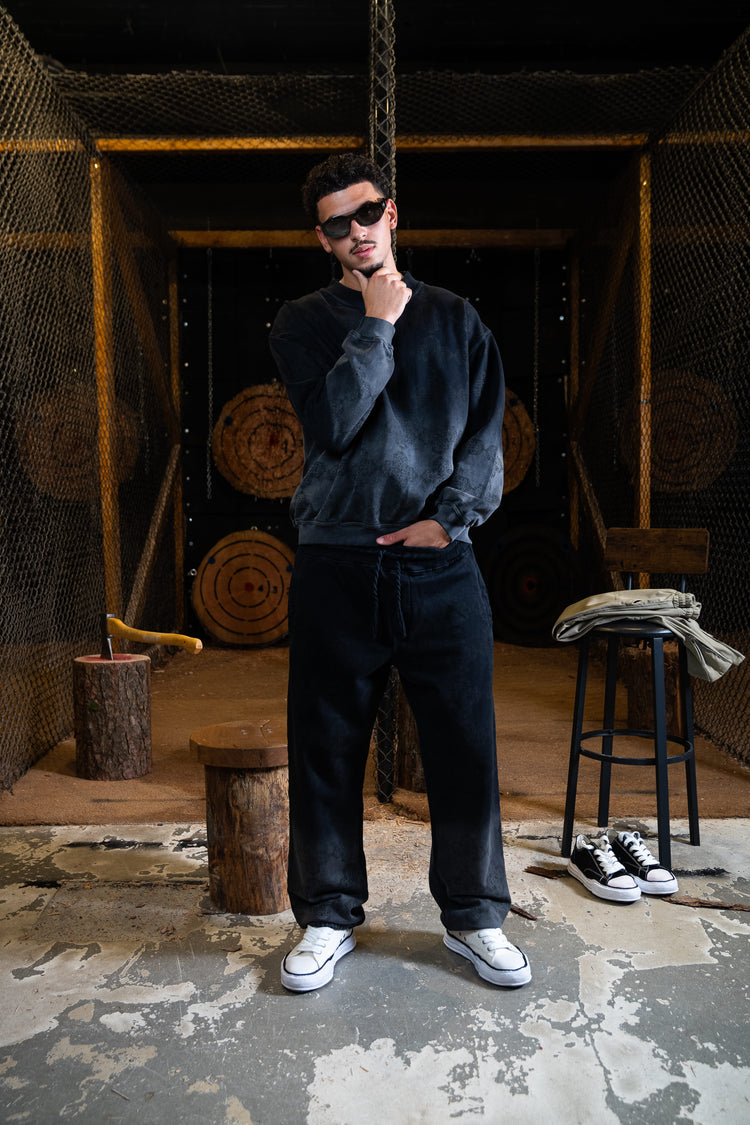 Model posiert in einem urbanen Setting, gekleidet in ein Decider Off Monogramm-Sweatshirt mit passenden Hosen