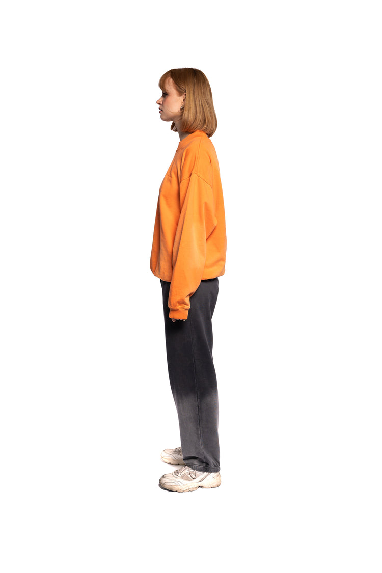 Seitenansicht des weiblichen Models im orangefarbenen Sweatshirt