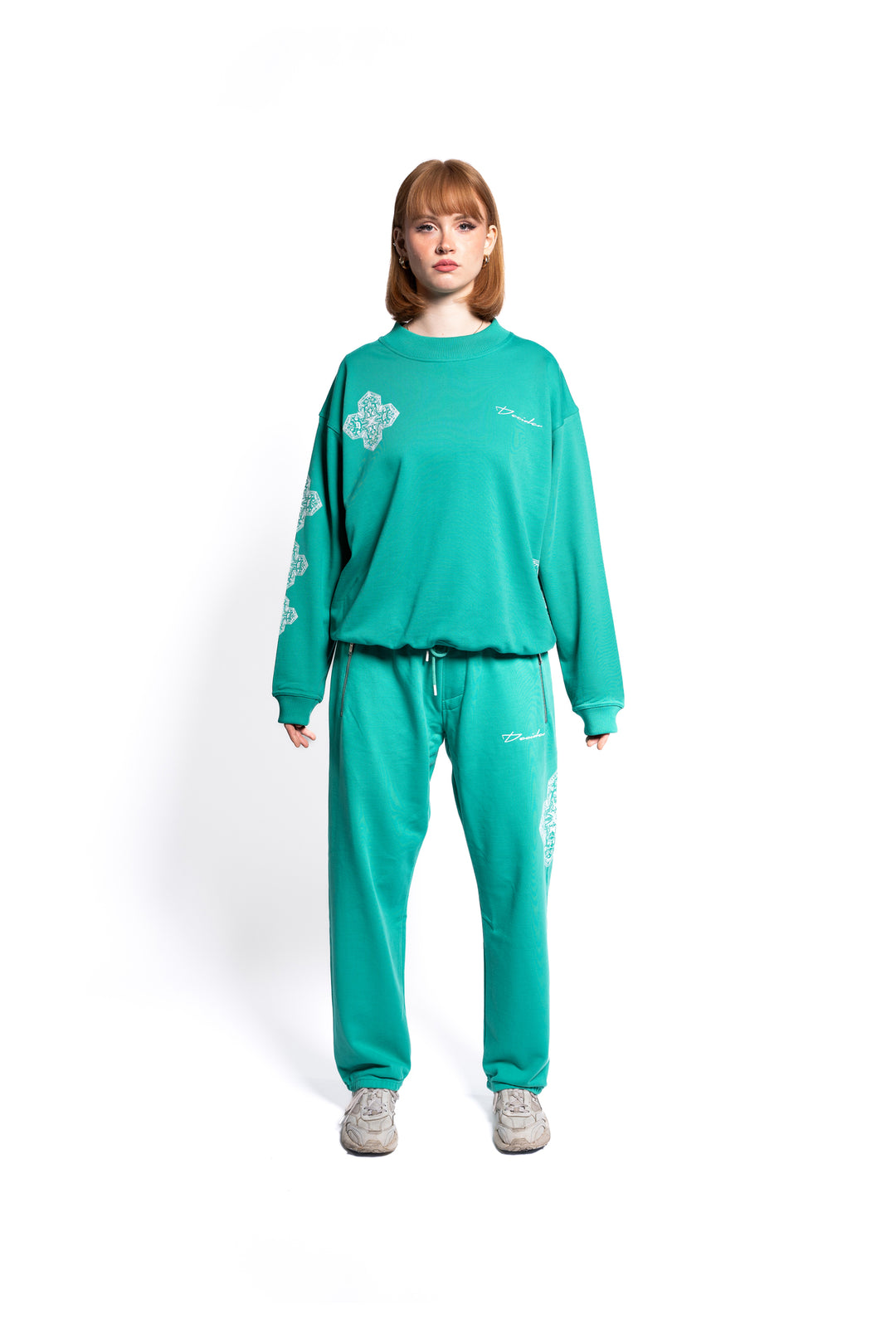 Weibliches Model präsentiert ein smaragdgrünes, übergroßes Sweatshirt mit passender Jogginghose, die mit weißen Mustern akzentuiert ist